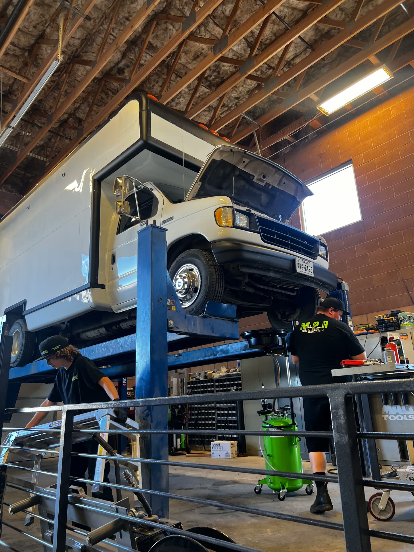 MPA technicians servicing a Ford E-350 box van up on the two-post lift