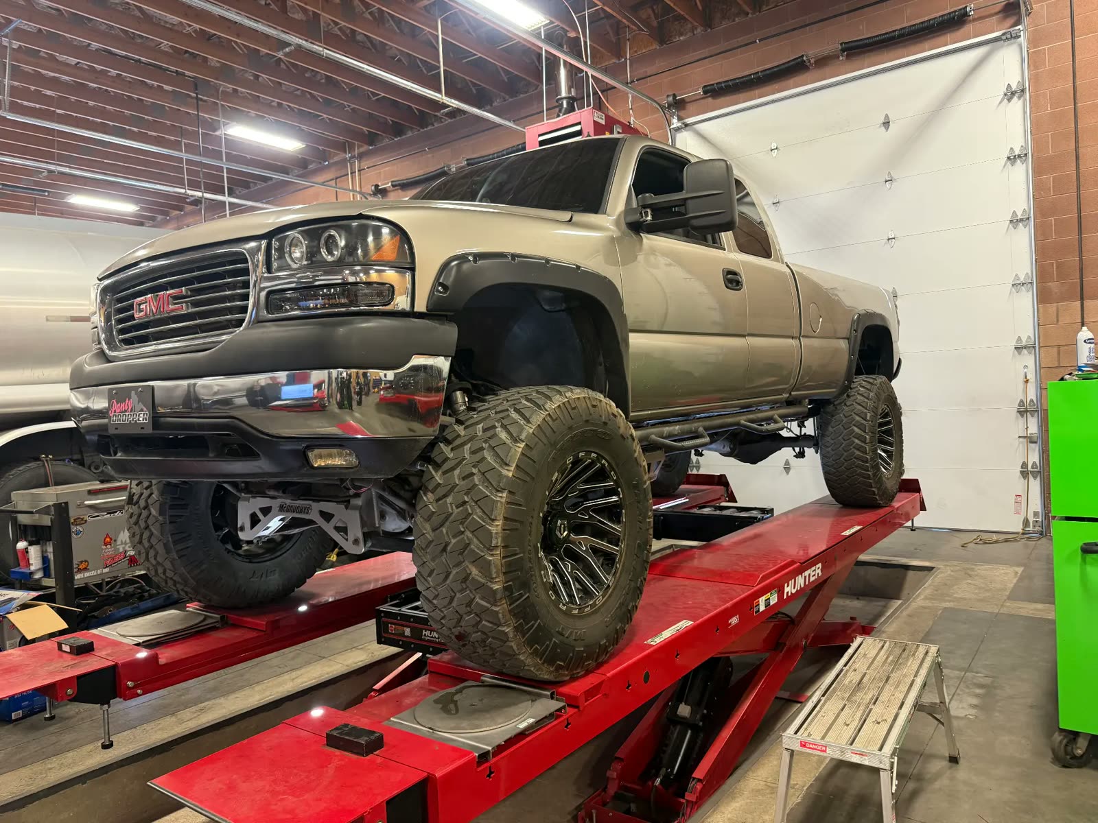 Lifted GMC Sierra on oversized tires up on the alignment rack