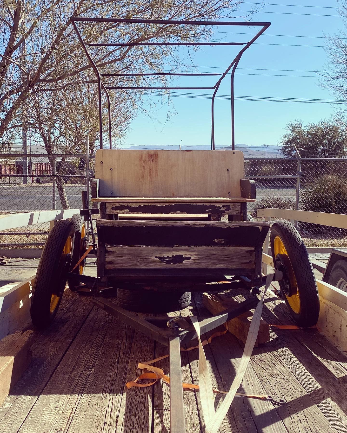 Antique wagon strapped to a flatbed trailer outside the MPA shop