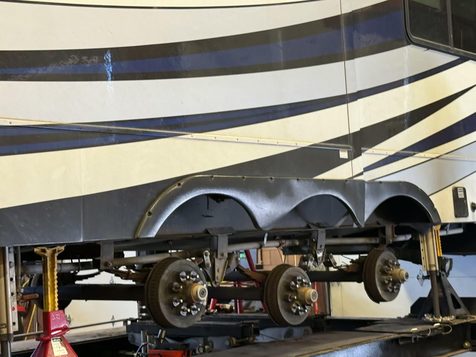 Underside of a Class A motorhome showing the tag axle and suspension on the rack