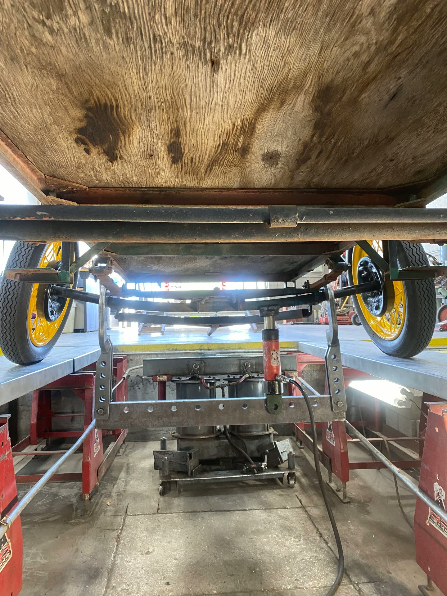 Underside of an antique horse-drawn wagon showing leaf springs and straight axle on the rack
