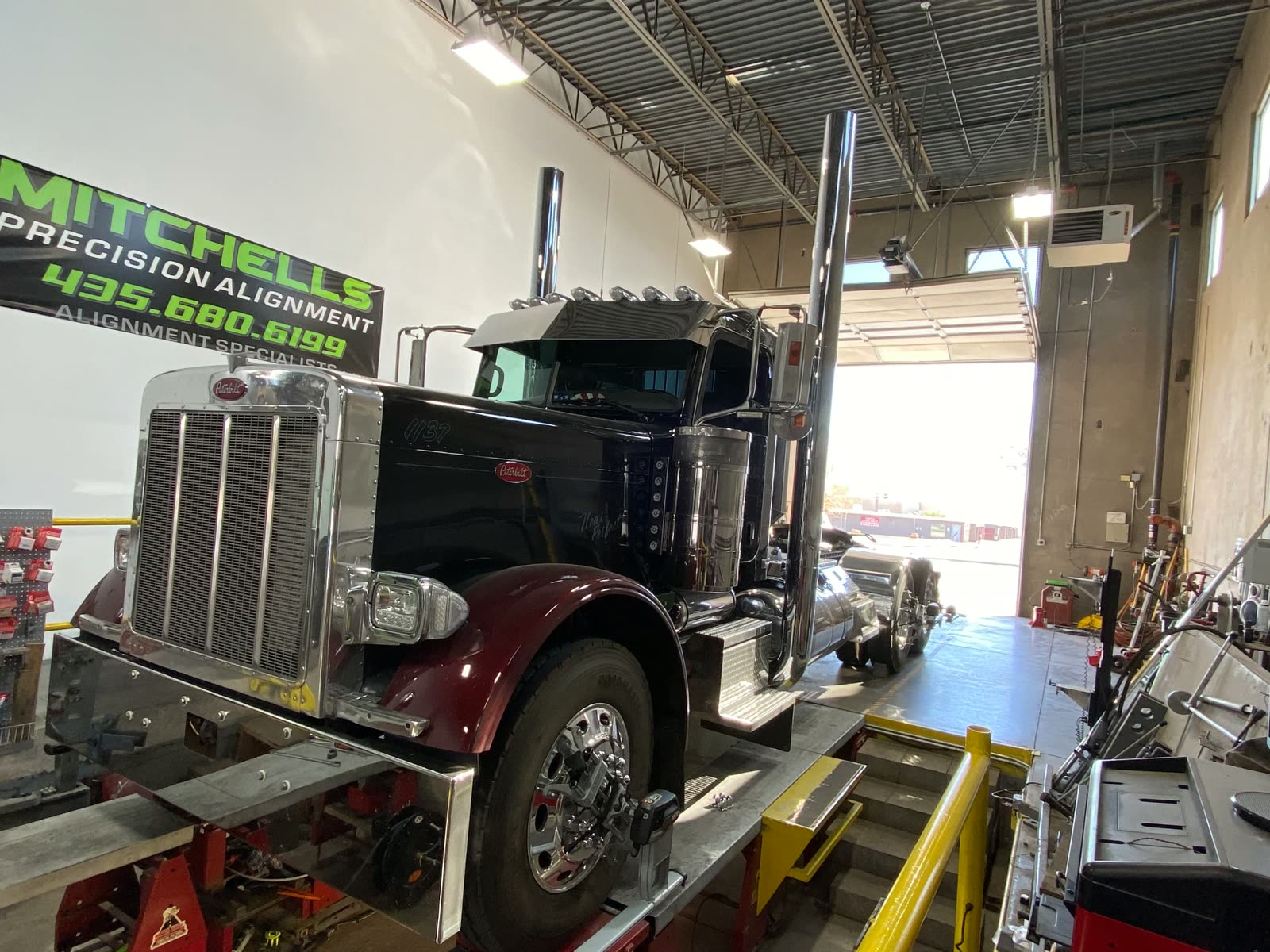 Black and maroon Peterbilt 389 on the heavy duty alignment rack under the MPA banner